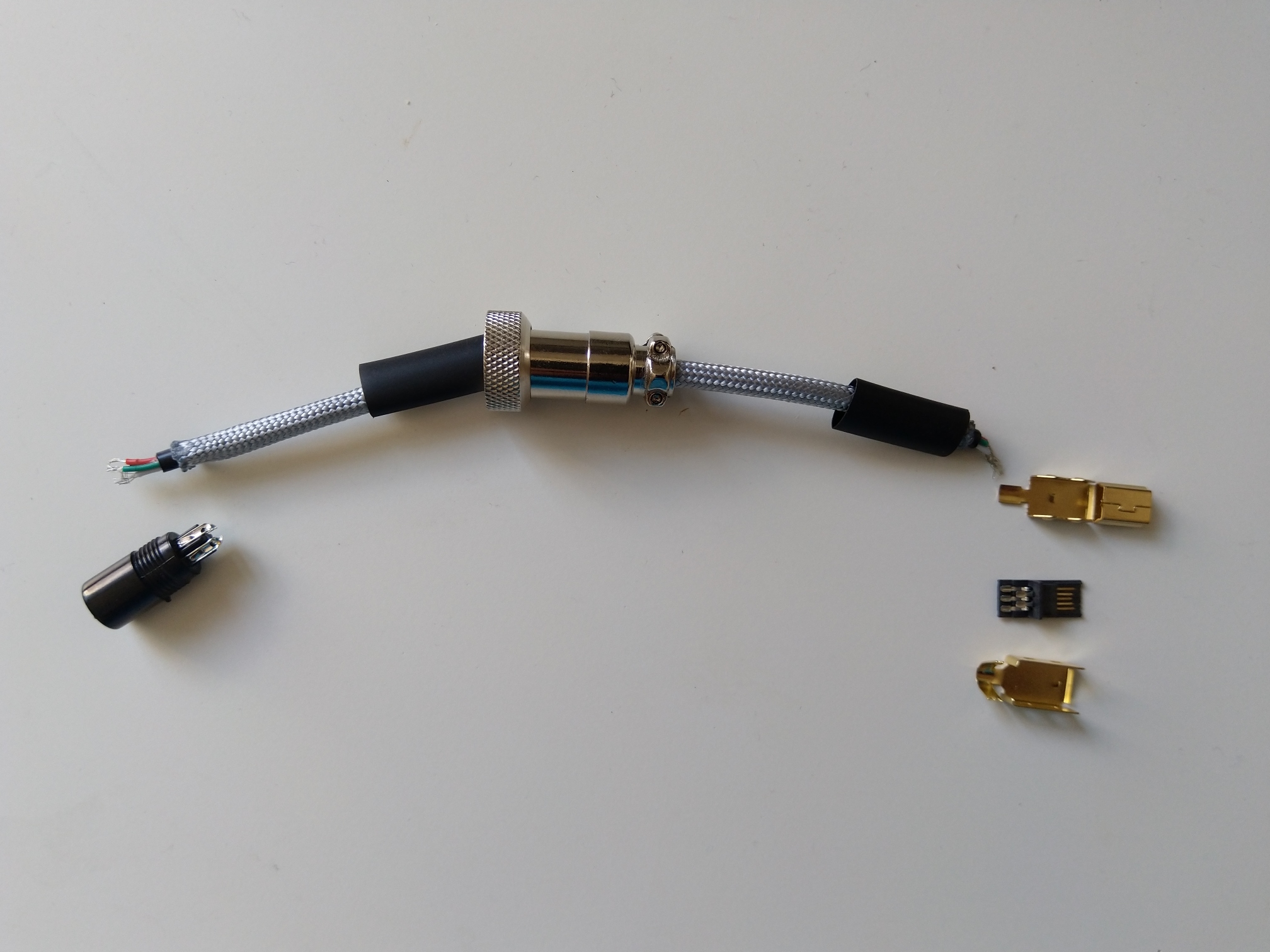 A shorter piece of cable (between the USB-mini and the aviation connector) already sleeved together with pieces of connectors and heat-shrinks. Sleeving is easy, just push the cable through the paracord. I have fixed it at ends with a drop of super glue.